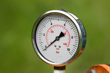 Close up of manometer measuring water pressure. Pipes and valves at industrial plant.
