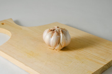 Garlic bulb on a wooden cutting board isolated on a white background
