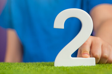 White number 2 in hand. The hand holding the number 2 symbolizes choice, partnership and duality,...