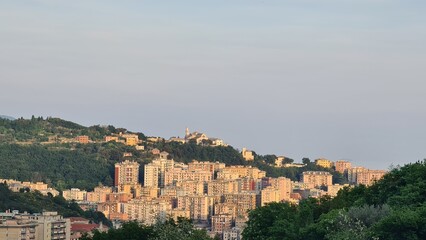 Fototapeta na wymiar Genoa, Italy - May 6, 2023: Top view of the city of Genoa at sunset from the mountains. Aerial view of Genoa and Sampdoria soccer teams stadium in Genoa Marassi in Italy.