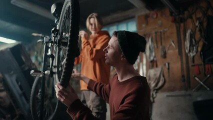 Dad and son work in the garage, they check if the chain on the bike is working