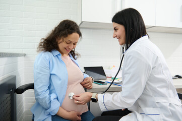 Confident female doctor obstetrician gynecologist checking heartbeat of the baby in womb using a...