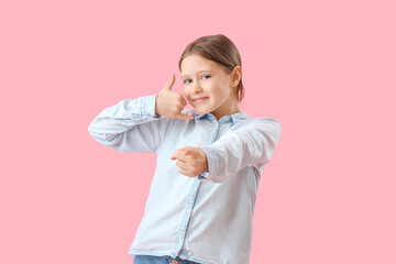 Little girl showing "call me" gesture on pink background