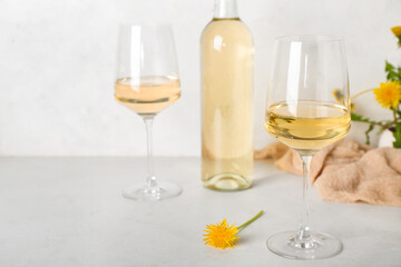 Bottle and glasses of dandelion wine on white table