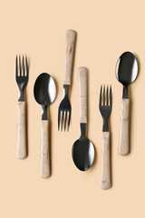 Stainless steel forks and spoons with plastic handles on beige background