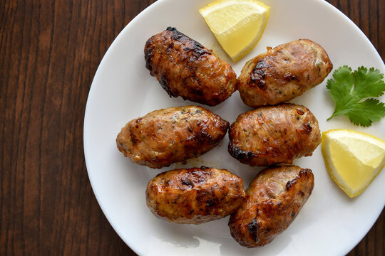 Sheftalia Cypriot lamb and pork Sausage. Grilled Sausages with lemon and coriander on a white plate. Traditional Cypriot food.