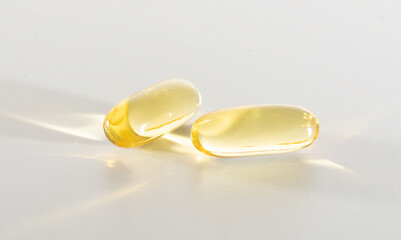 Fish Oil Omega 3 on white background, vitamin D yellow supplement gel capsules, macro shot
