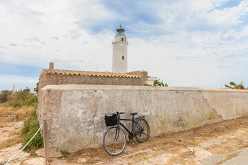 A touring bicycle parked next to the lighthouse of La Mola, on the island of Formentera. Balearic...