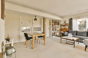 a living room with couches, tables and books on the shelves in the room is very light gray color