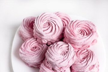 tasty homemade zephyr marshmallows with blackberries taste inside whisk wires or in fork,black gray tiles background,kitchen towel.tea in cup and kettle,marshmallow on plate.close up texture macro