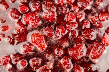 Process of making homemade raspberry jam. Red sweet syrup boiling on the stove closeup. Strawberry jam looks very appetizing. Boiling homemade strawberry jam. Make a strawberry jam.