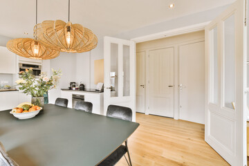 a kitchen and dining area in a house with white walls, hardwood flooring and an island table...