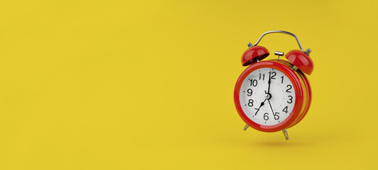 Red alarm clock hangs in the air on yellow background