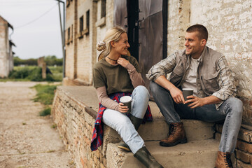Two young adults are sitting on the stairs outside and having an enjoyable conversation