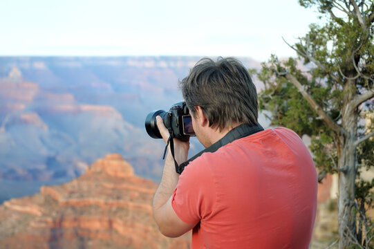 Middle age male tourist making photo of the famous Grand Canyon from Mather Point. Handsome man traveling and admiring sightseeing.
