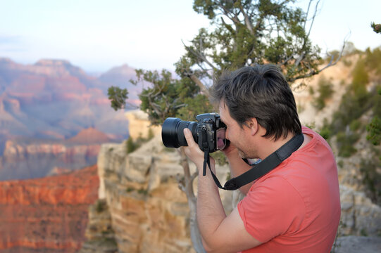 Middle age male tourist making photo of the famous Grand Canyon from Mather Point. Handsome man traveling and admiring sightseeing.