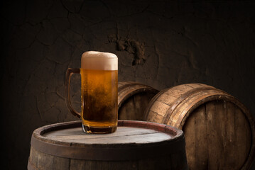 mug of beer, wheat ears, green hops and beer barrel on a wooden background. High quality photo