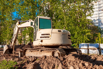 Obraz premium An excavator working on a construction site against the background of sunset. The excavator digs up gravel and earth.