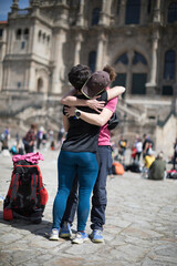 Pilgrims on the Camino de Santiago arrive at the Plaza del Obradoiro because they have finished their pilgrimage. Two pilgrims embrace upon their arrival at the Cathedral of Santiago de Compostela - obrazy, fototapety, plakaty