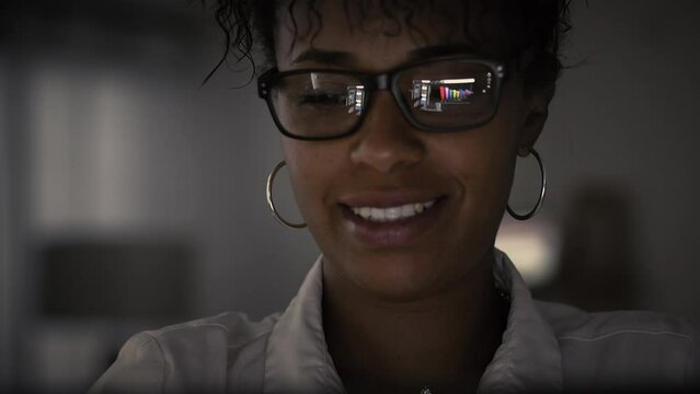 Lateral Dolly of Young Focused African American Businesswoman in Eye Glasses Late at Night Working in Front of Computer. Finance  Stock Exchange Animations. Female Broker 