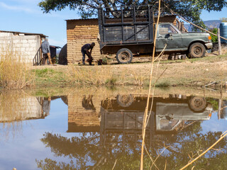 Personas trabajando, camioneta reflejo en el agua, casa de campo