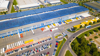 Aerial view of modern storage warehouse with solar panels on the roof. Logistics center in industrial city zone from drone view. Background texture concept.