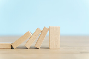 Falling wooden domino cubes. Insurance, business, risk, management concept.