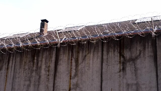 many rows of barbedwire, high concrete fence, barbed wire fence on top, building for execution of punishments for criminals, concept prison, security zone, symbol of bondage, hopelessness of captivity