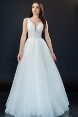 Fototapeta premium Beautiful bride in wedding dress on black background