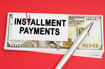 On a red surface are dollars on which a pen and paper with the inscription - installment payments