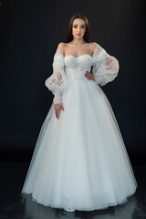 Fototapeta premium Beautiful bride in wedding dress on black background