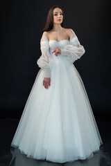 Fototapeta premium Beautiful bride in wedding dress on black background