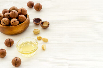 Bowl of of macadamia nuts oil with raw nuts. Natural oil for cosmetic or cooking