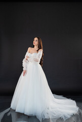 Fototapeta premium Beautiful fashion bride posing in wedding dress on black background 