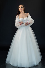 Fototapeta premium Beautiful fashion bride posing in wedding dress on black background 