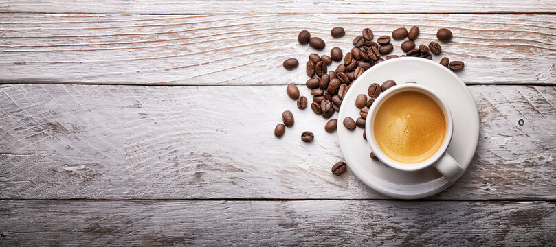 Espresso cup with coffee beans on white wooden background, top view, copy space, flat lay.