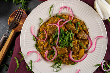 Lamb tajine: Leg of lamb, vegetables, and dried apricots braised in a tajine with a coconut milk/curry sauce. Served with couscous and garnished with pickled red onion and spinach
