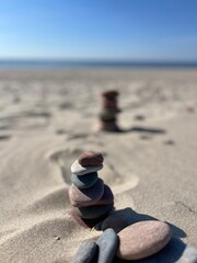 Obraz premium Small stones pyramid on the sand, sandy beach, sea horizon 