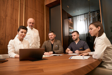 Doctors and patient looking at laptop at desk