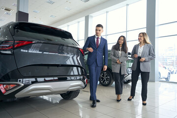 Female lgbt couple and manager on car review in car dealership