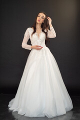 Fototapeta premium Beautiful fashion bride posing in wedding dress on black background 