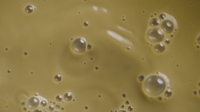 Top view of cappuccino coffee into which ice cubes are being dropped in slow motion.