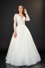 Fototapeta premium Beautiful fashion bride posing in wedding dress on black background 