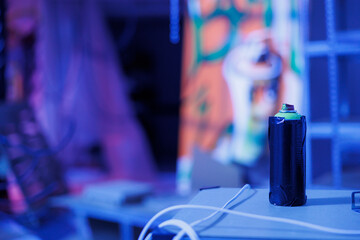 Aerosols paint cans in abandoned glowing space filled with graffiti artwork on rusty walls,...