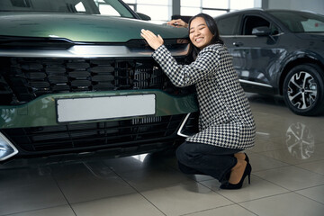 Exalted beautiful woman hugging a shining car hood