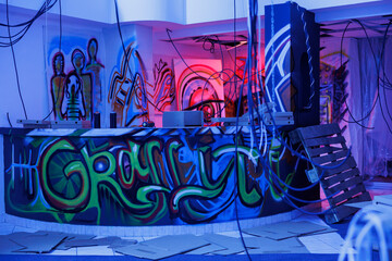 Graffiti art on rusty walls glowing with bright neon lights, looking artistic in abandoned old space. Damaged crumbling building illuminated by fluorescent glowy light, damaged place.