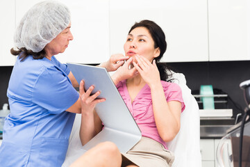 Obraz premium Doctor beautician discussing with woman cosmetological procedure in clinic