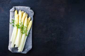 White asparagus glazed with cress served as top view on a design tray with text space right