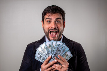 Hombre sosteniendo muchos billetes dólares y con una expresión de alegría