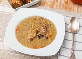 Appetizing pork and mushroom soup with vegetables and pearl barley. Comfort food .